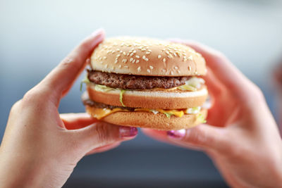 Close-up of hands holding hamburger outdoors