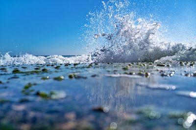 Close-up of water splashing in sea against clear blue sky