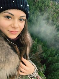 Portrait of smiling beautiful woman wearing warm clothing in forest