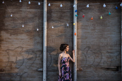 Side view of woman standing against brick wall