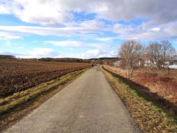 Road amidst field against sky
