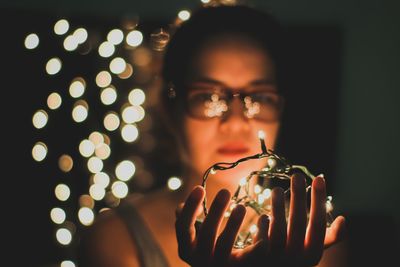 Close-up of woman holding illuminated lighting equipment