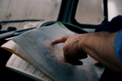 Male hand pointing to a map of scotland from inside a car