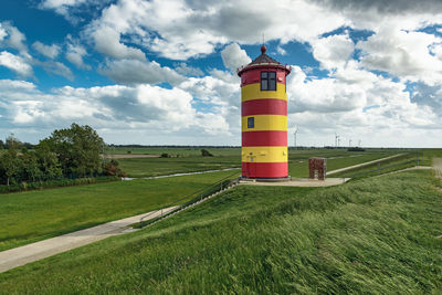 Lighthouse on field against sky