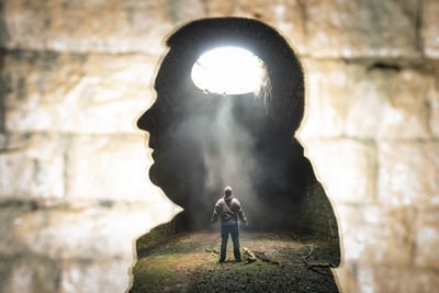 Side view of man standing against stone wall