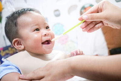 A happy asian baby boy sitting and feeding some pap pudding by mom with spoon.