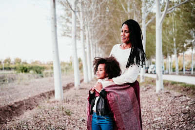 Mother and daughter looking away while standing at park