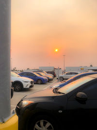 Cars on street against sky during sunset