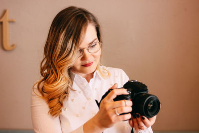 Young woman looking away while photographing with camera