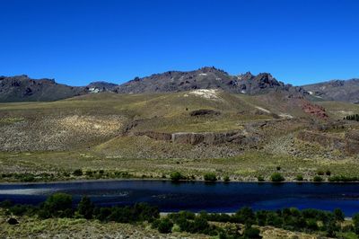 Scenic view of lake and mountains against clear blue sky