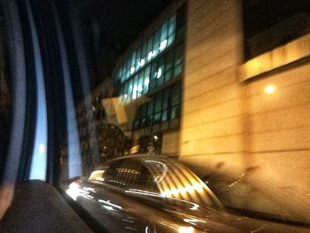 Cars on illuminated street amidst buildings at night