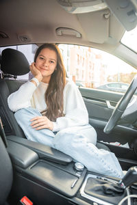 Portrait of young woman sitting in car