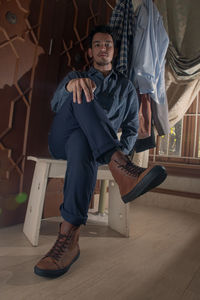 Portrait from lower angle of a brown leather sneakers worn by mixed race man sits on a white stool