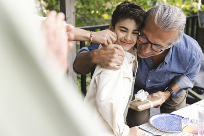 Senior man hugging grandson during midsummer dinner party