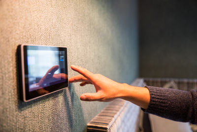 Cropped hand of woman touching device screen at home