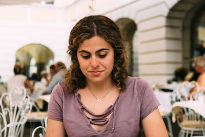 Smiling young woman sitting at sidewalk cafe