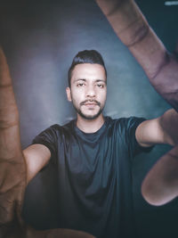 Portrait of young man standing against wall