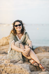 Young woman wearing sunglasses sitting on rock