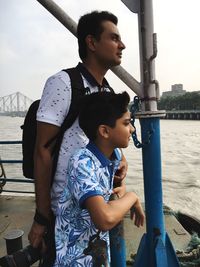 Side view of boy standing by water against sky