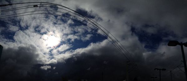 Low angle view of electricity pylon against cloudy sky