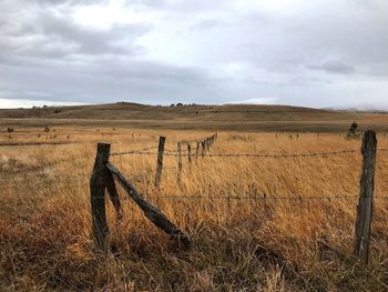 Wooden fence on field against sky