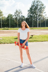 Portrait of a happy teenage girl holding a skateboard