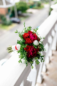 Bouquet of red roses and red and white peonies on a background of white stone railing