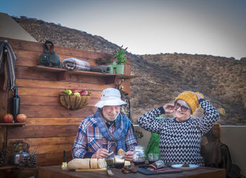 Senior couple sitting at restaurant against mountain range