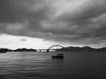 Bridge over river against cloudy sky