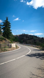 Road by trees against sky