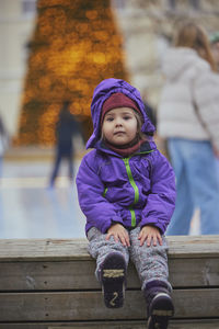 Portrait of cute girl sitting on boardwalk