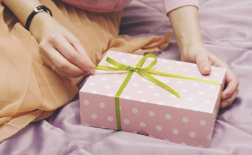 Midsection of woman holding gift box on bed at home
