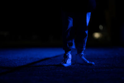 Low section of person standing on footpath at night