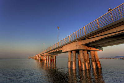 Bridge over sea against sky during sunset