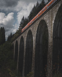 Low angle view of railway bridge against cloudy sky