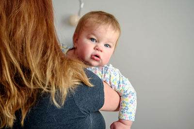 Cute girl of ten months old, playing in her mother's arms. happy childhood.