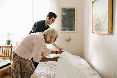 Side view of man sitting on bed at home