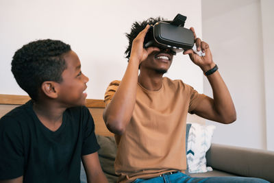 Boy sitting with father looking through virtual reality at home