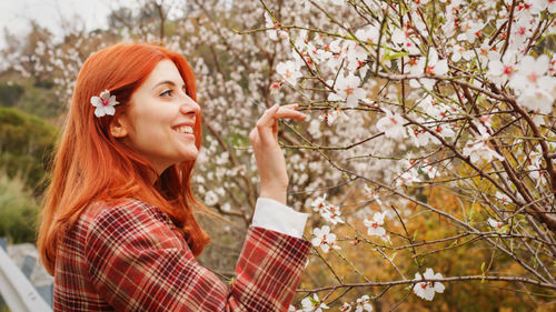 Happy red-haired girl under spring flower tree. spring mood.