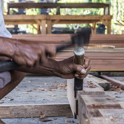 Cropped hands of carpenter with wood working outdoors