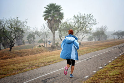 Rear view of woman running on road