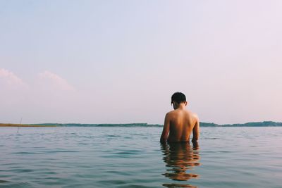 Rear view of man standing in sea against sky