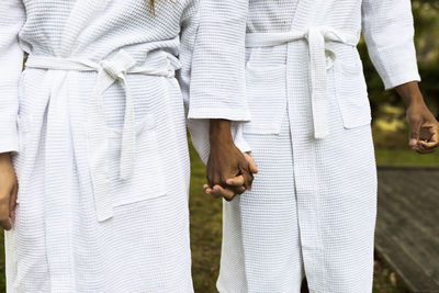 Close-up of couple in bathrobes holding hands