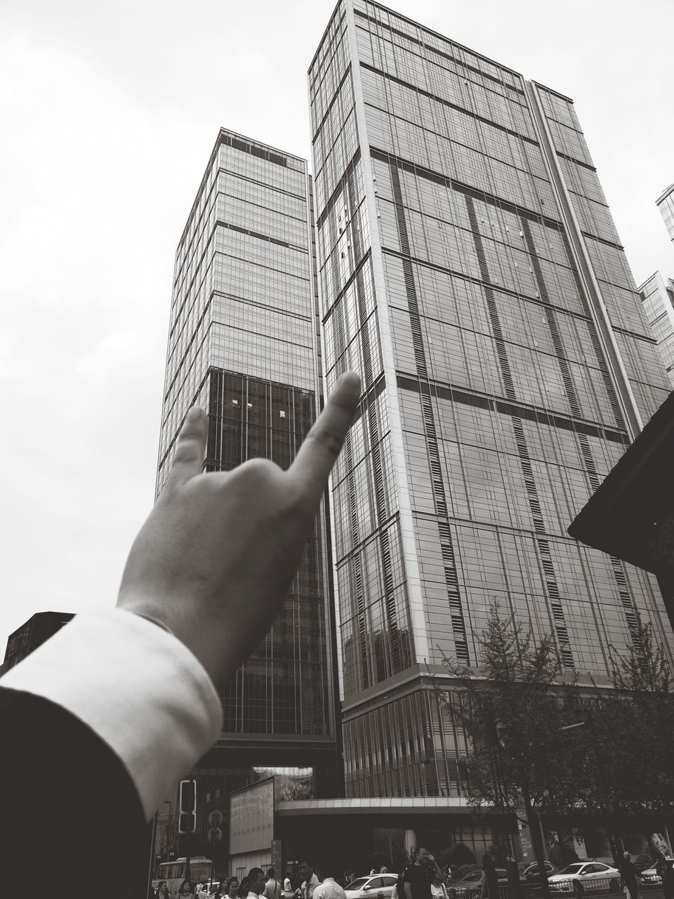 human hand, architecture, building exterior, human body part, skyscraper, city, built structure, human finger, one person, personal perspective, sky, real people, urban skyline, day, outdoors, modern, business finance and industry, cityscape, people, adult, adults only