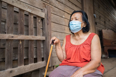 Senior woman wearing mask sitting outdoors