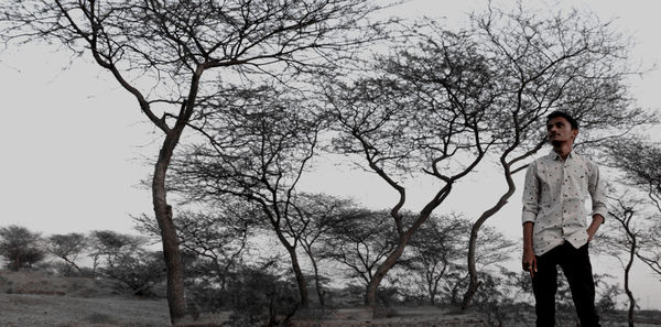 Woman standing by bare tree against plants