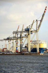 Cranes at commercial dock against sky