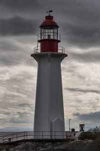 Low angle view of lighthouse by building against sky