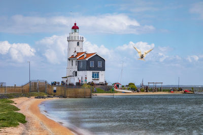 Lighthouse amidst buildings in city against sky