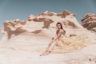 Woman standing on rock formation in desert against sky